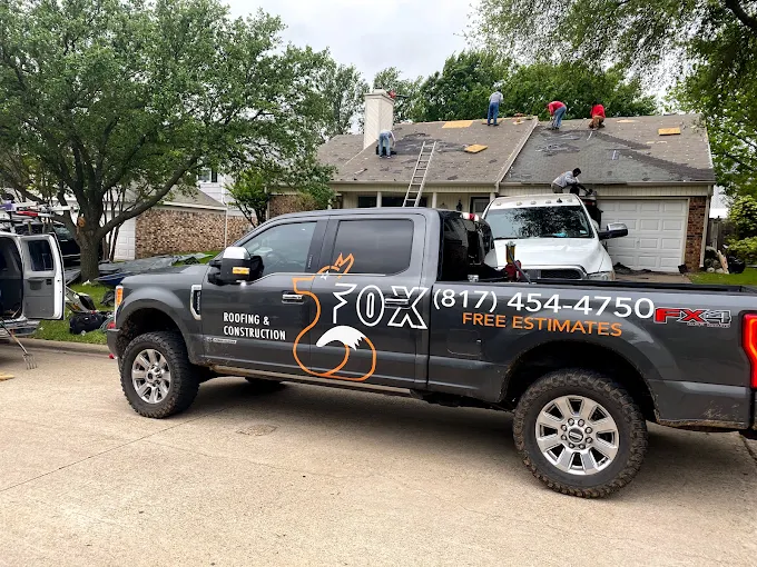 Fox Roofing crew replacing a roof in Springtown with the branded truck parked out front