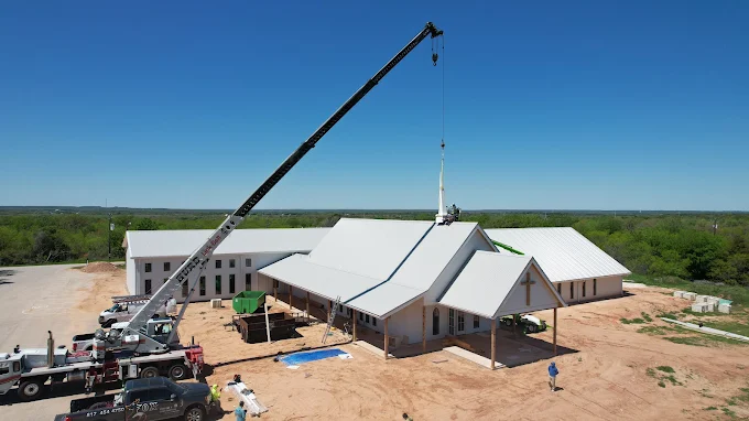 Crane lifting a new steeple onto a Springtown church re-roof project